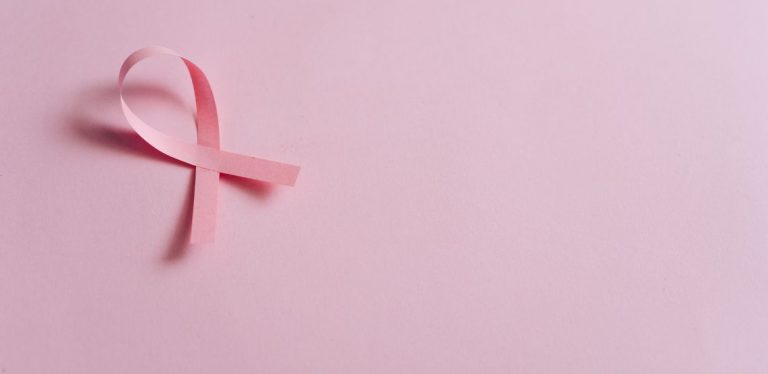 A breast cancer ribbon on a light pink background.