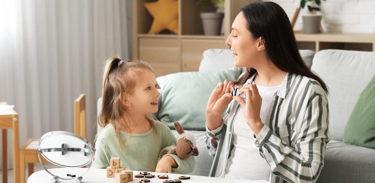 A child sitting with a speech therapist, learning how to pronounce letters.